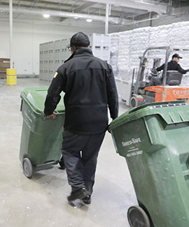worker moving two shredding bins in warehouse