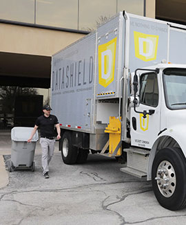 a DataShield employee loading a bin onto shred truck